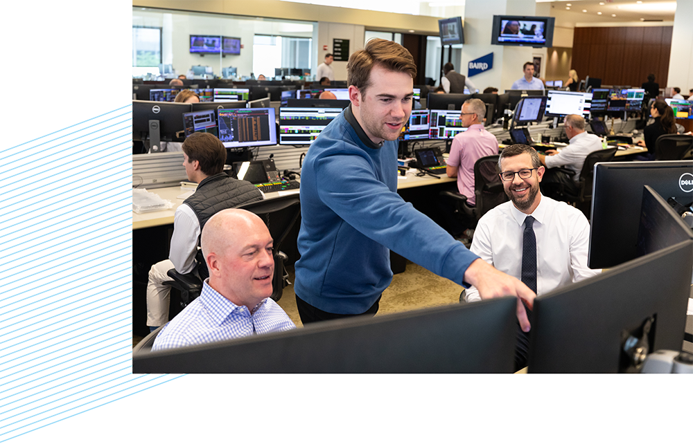 Three RJF Pro associates looking at computer monitors on the trading floor